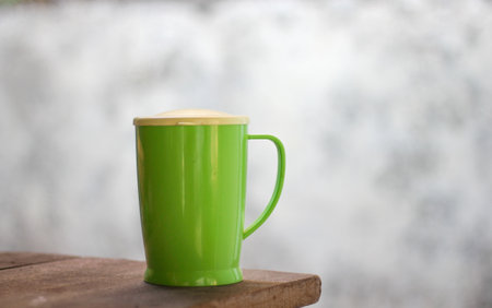 Green coffee cup on wood table and white cement wall background, stock photo