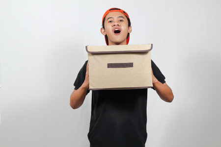 young man holding a cardboard box on white background.