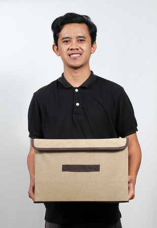Portrait of a happy young man holding a cardboard box isolated on white background