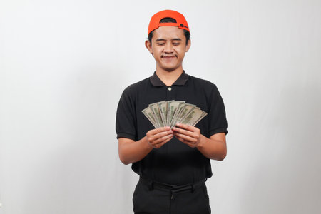 Portrait of happy young Asian man counting money on white background.