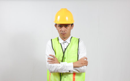 Portrait of Asian male engineer wearing safety vest and hardhat with crossed arms