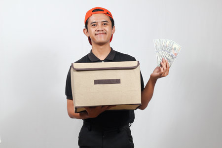 asian delivery man in black uniform holding money and box on white background