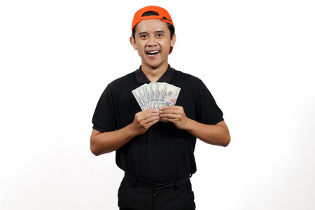 asian man in black t-shirt and cap holding money on white backgroundの写真素材