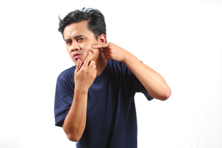 Asian man scratching his pimple on his face. Isolated on white background