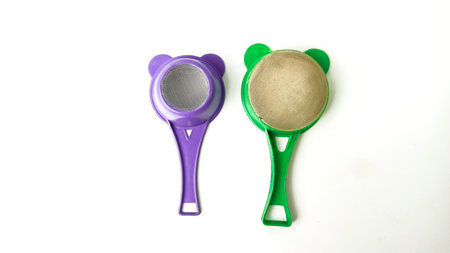 Green and purple plastic measuring spoons isolated on a white background.