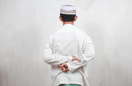 Back view of muslim man with traditional clothes praying over white background