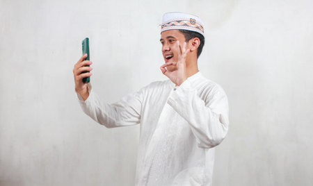Portrait of young asian muslim man taking selfie with mobile phone