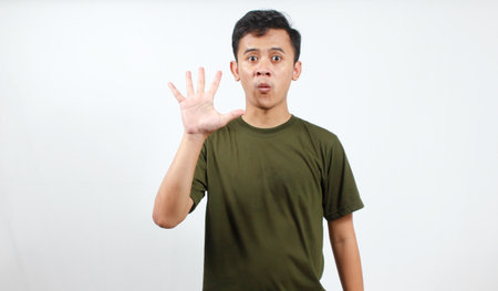 Portrait of a young Asian man making stop gesture on white background