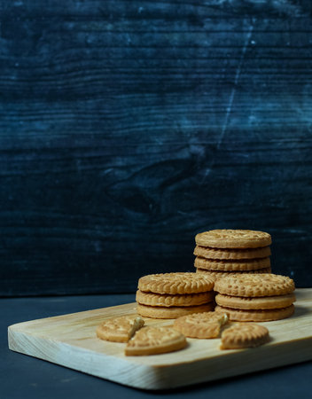 Sandwich cookies on a wooden board. Dark background. Copy space.