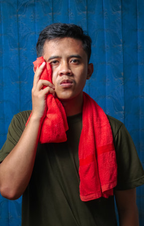 Portrait of Asian man wiping his face with a towel.