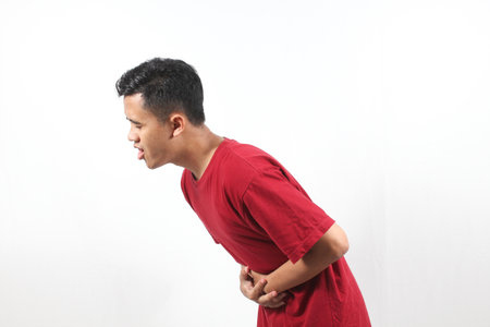 Young Asian man suffering from backache, isolated on white background.の写真素材