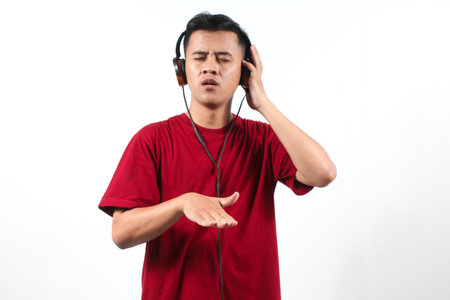 Young asian man listening to music with headphones on white background.