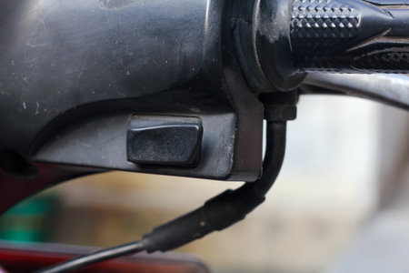 Close-up of a motorcycle handlebar with a plug in.