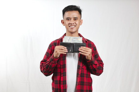 Young man holding a wallet full of money on a white background.