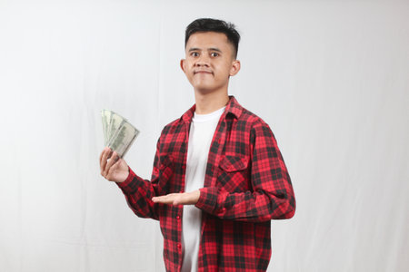 Portrait of a young asian man holding money on white background