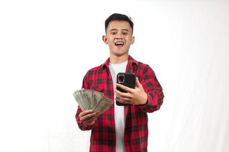 Young asian man using mobile phone and holding money on white background