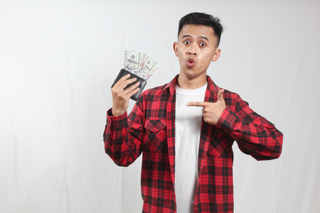 Young asian man in checkered shirt holding money on white background