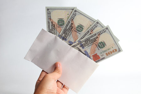 Hand holding envelope with money isolated on white background. Concept of corruption and bribery.