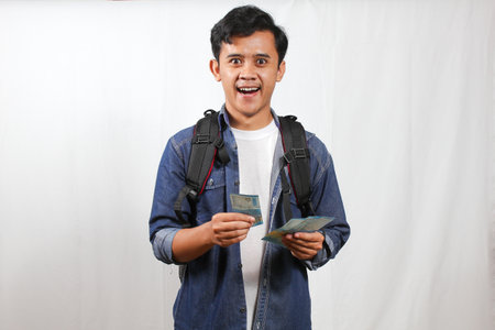 young asian backpacker man holding money and smiling at camera