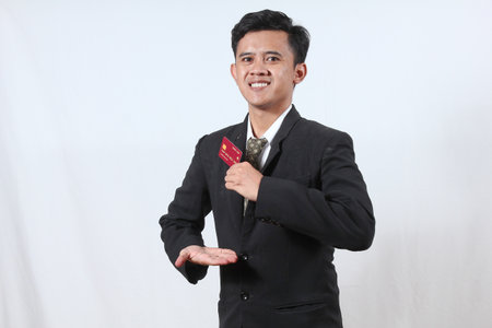 Young asian man holding a red credit card on white background.の写真素材