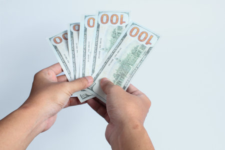 Hand holding 100 dollar banknotes isolated on white background with clipping path