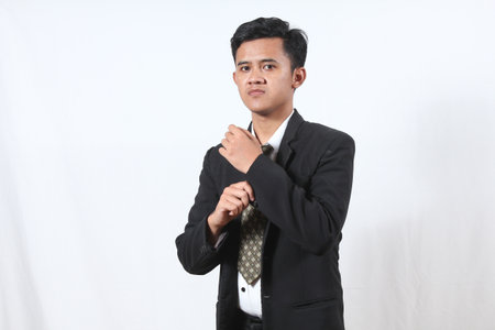Portrait of a young Asian businessman adjusting his necktie on white backgroundの写真素材