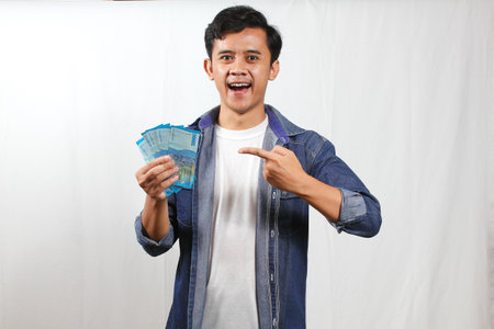 Portrait of a happy young asian man showing money banknotes