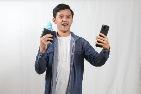 Portrait of a young man using mobile phone and holding passport.