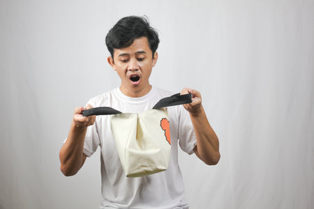 Surprised shopper peers into reusable tote bag after grocery run, a sustainable lifestyle choice for...