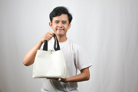 Portrait of Asian man holding a white bag on white background.の写真素材