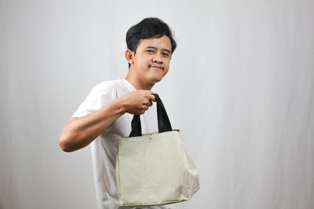 Portrait of Asian young man holding bag. Isolated on white background.の写真素材