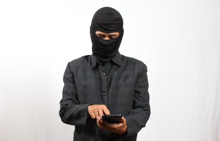 Asian man wearing a balaclava using mobile smart phone on white background
