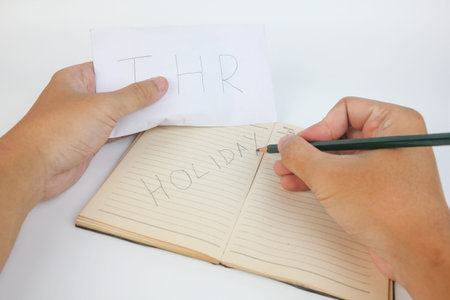 Woman writing the word home in notebook with pencil on white background.の写真素材