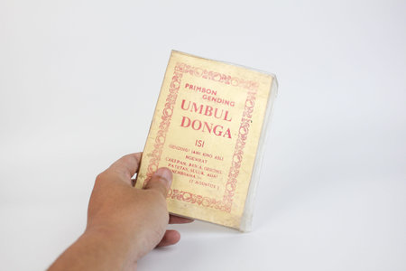 Indonesia, Sukoharjo - February 14, 2026: hand holding primbon gending umbul donga book isolated on white backgroundのeditorial素材