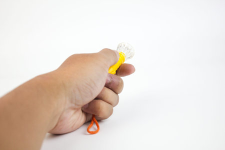 Hand holding a yellow and white object with an orange string on a white background.の写真素材