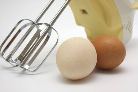 mixer and two eggs on white background
