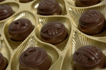 Box of chocolates inside. Dark chocolate in gold foil.の写真素材