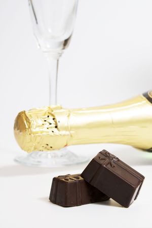 Empty wineglass, closed bottle of champagne and chocolate sweets. Concept of a coming nearer holidayの写真素材