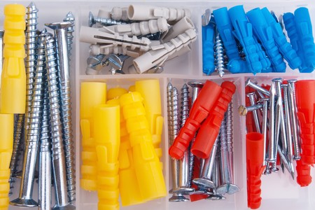 Screws and colored plugs in plastic toolbox, top view