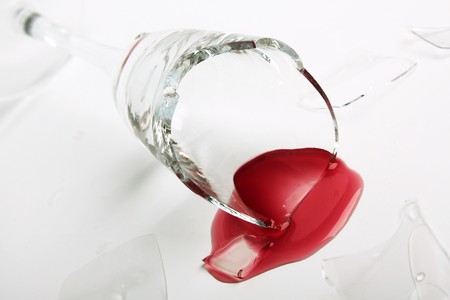 Broken wineglass on the table. Poured red wine, like blood.の写真素材