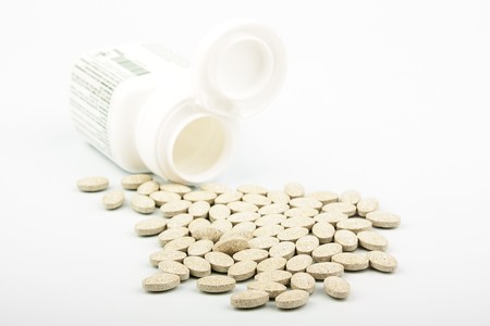 Heap of grassy tablets with a jar on a white background
