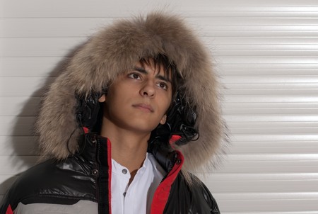 Portrait of a handsome young man of sixteen. Youth shows autumn, winter clothing.