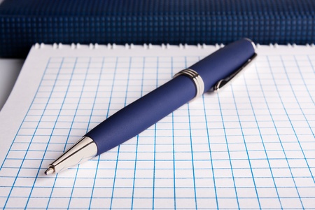 The blue ball pen lays on a notebook, a writing-book.の写真素材