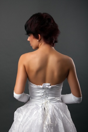 back view of beautiful brunette bride over gray studio backgroundの写真素材