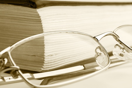A pair of glassess setting on the book in sepiaの写真素材