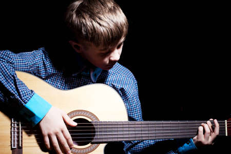 Young Boy Holding Guitar on Black Backgroundの写真素材
