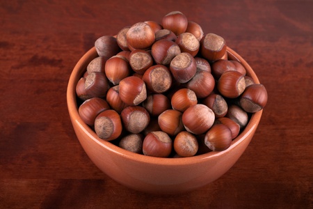 brown earthenware dish with nuts on a wooden tableの写真素材
