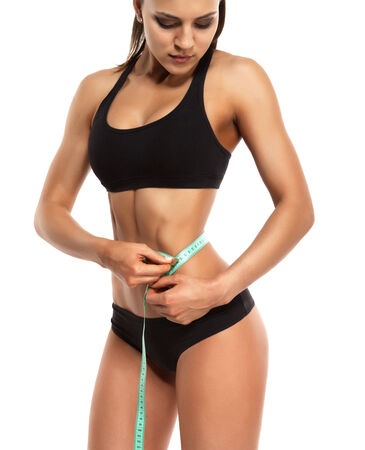 beautiful young woman measuring her thin waistの写真素材