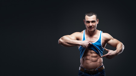 Bodybuilder showing his press. A man shows his abdominal muscles, raised his hand t-shirt. Press, muscles, show, bodybuilding. Sports guy.の写真素材