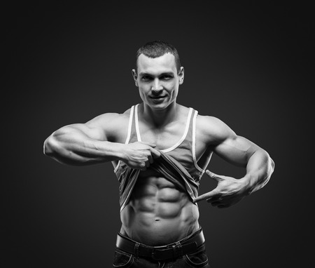 Bodybuilder showing his press. A man shows his abdominal muscles, raised his hand t-shirt. Press, muscles, show, bodybuilding. Sports guy.の写真素材